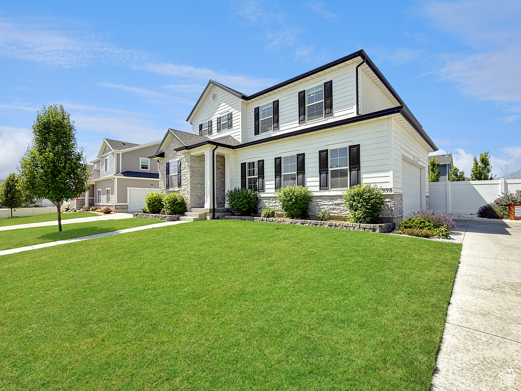 View of front facade with concrete driveway, stone siding, and an attached garage