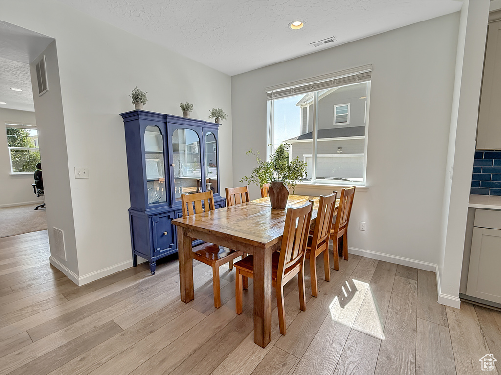Dining room with light wood finished floors, healthy amount of natural light, recessed lighting, and a textured ceiling