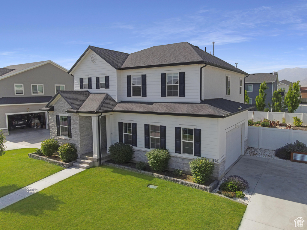 Traditional-style home with a garage, driveway, roof with shingles, and stone siding