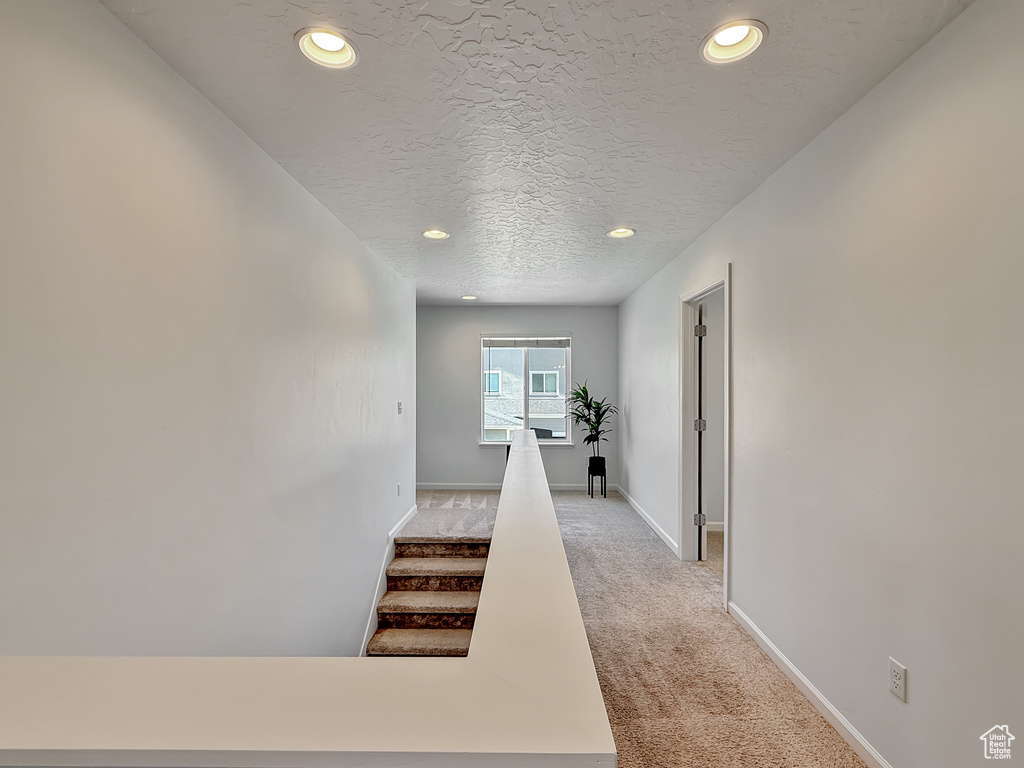 Corridor featuring light carpet, recessed lighting, a textured ceiling, and stairway