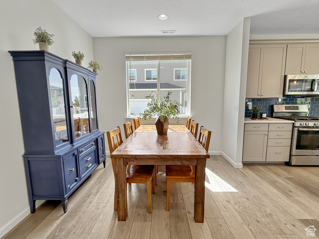 Dining room with light wood finished floors and recessed lighting