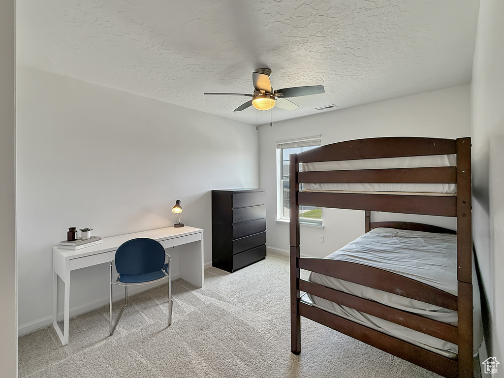 Carpeted bedroom with a textured ceiling, an office area, and ceiling fan