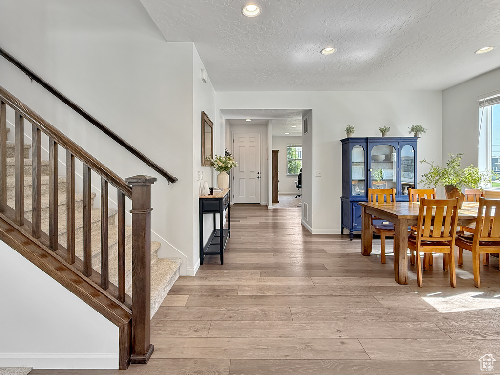 Dining area featuring light wood-style flooring, stairs, a textured ceiling, and recessed lighting