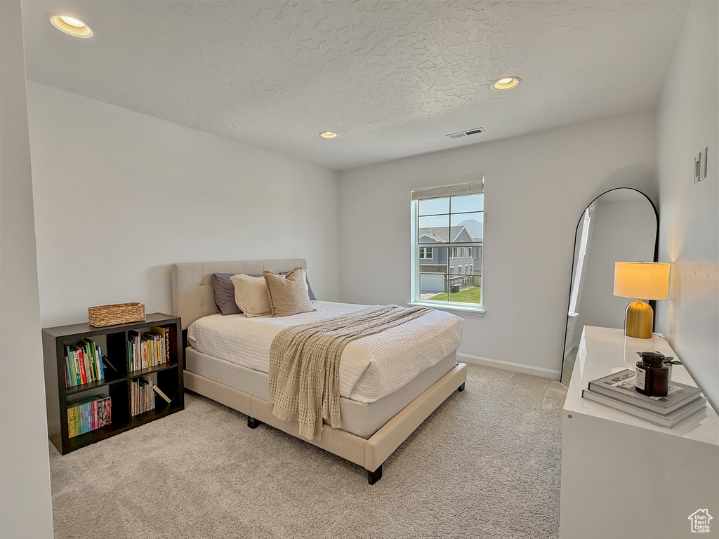 Bedroom with light colored carpet, recessed lighting, and a textured ceiling