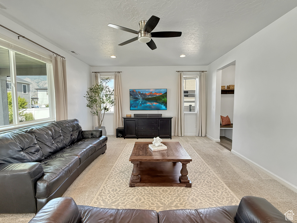 Carpeted living area with ceiling fan and recessed lighting