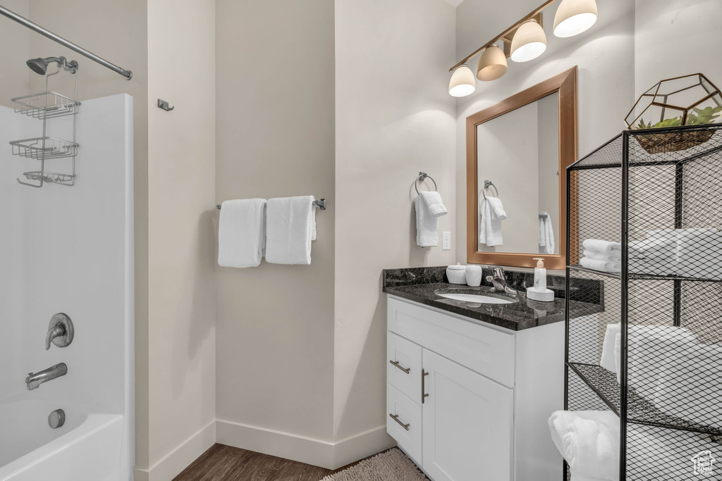 Bathroom featuring vanity, shower / bath combination, and wood finished floors
