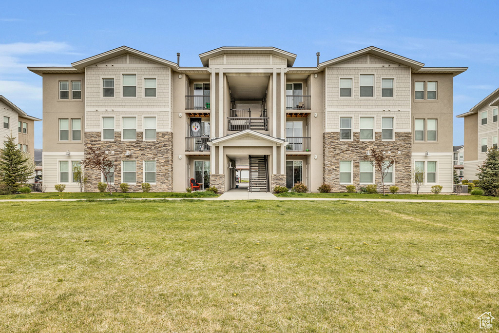 View of front of house featuring stone siding and a front lawn