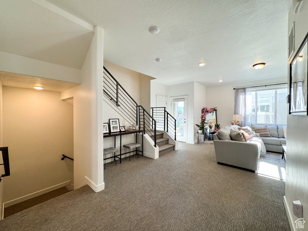 Living room with carpet, stairs, a textured ceiling, and recessed lighting