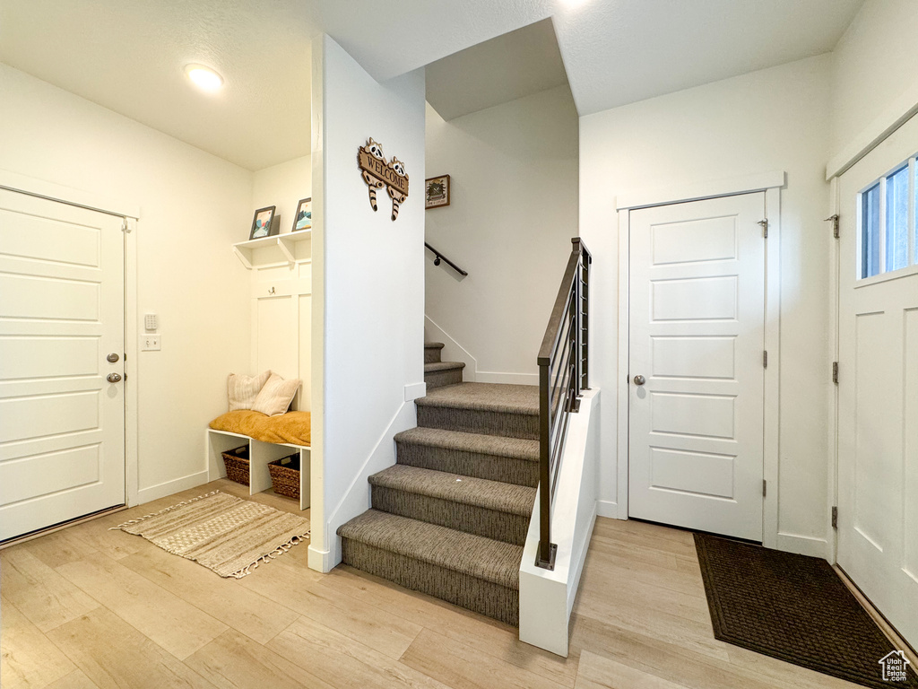 Entryway with light wood finished floors, stairway, and recessed lighting
