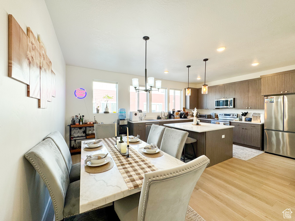 Dining space with light wood-type flooring, a chandelier, and recessed lighting