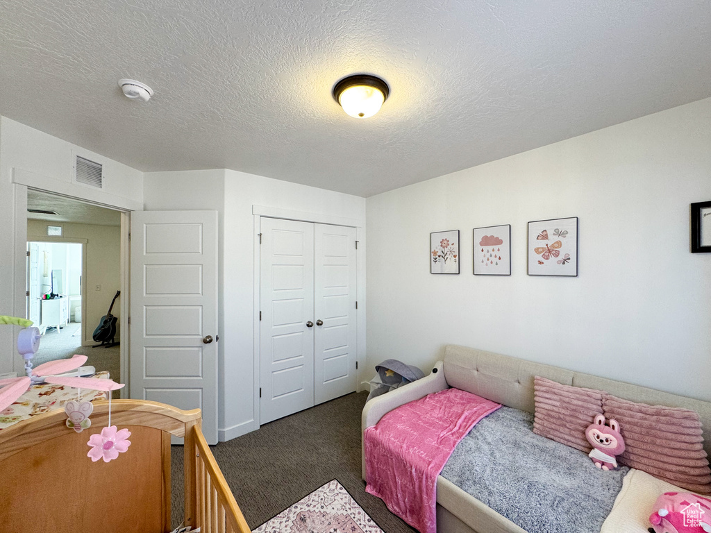 Carpeted bedroom with a closet and a textured ceiling