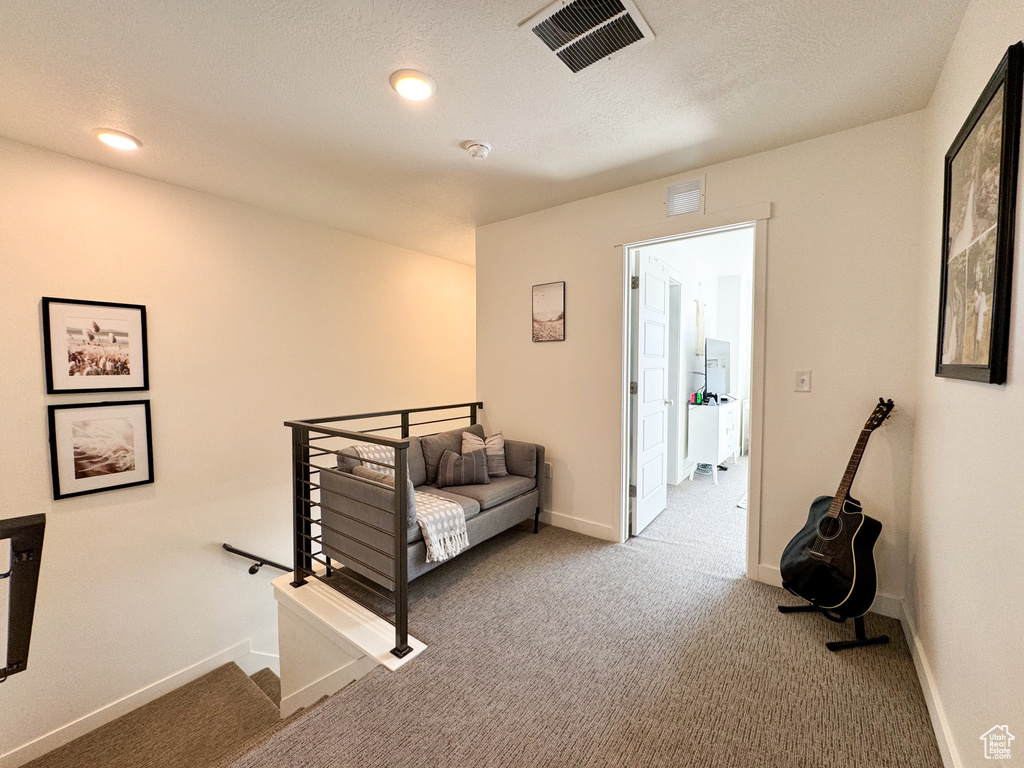 Hallway with an upstairs landing, carpet, and a textured ceiling