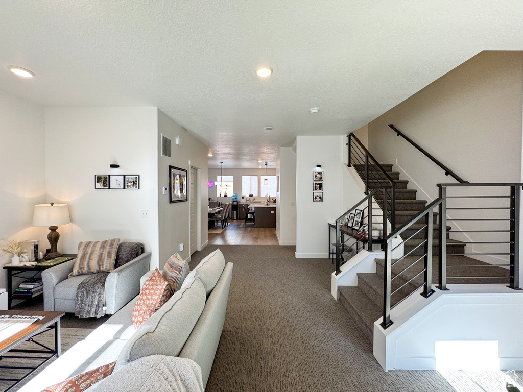 Carpeted living area featuring stairway and recessed lighting