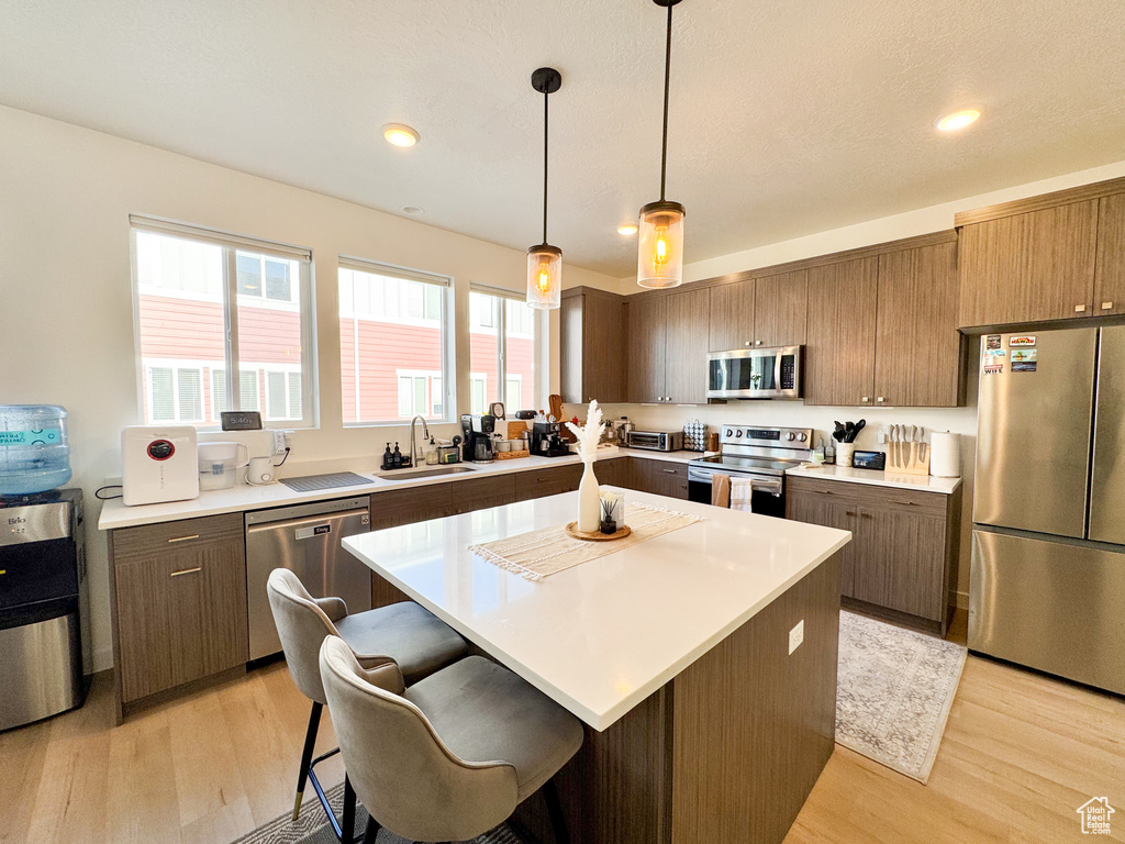 Kitchen with appliances with stainless steel finishes, light wood-style floors, light countertops, and recessed lighting