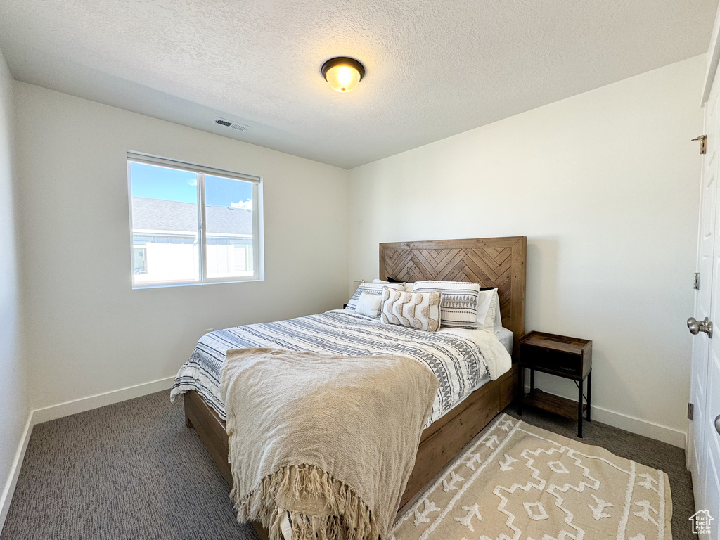 Carpeted bedroom featuring baseboards and a textured ceiling