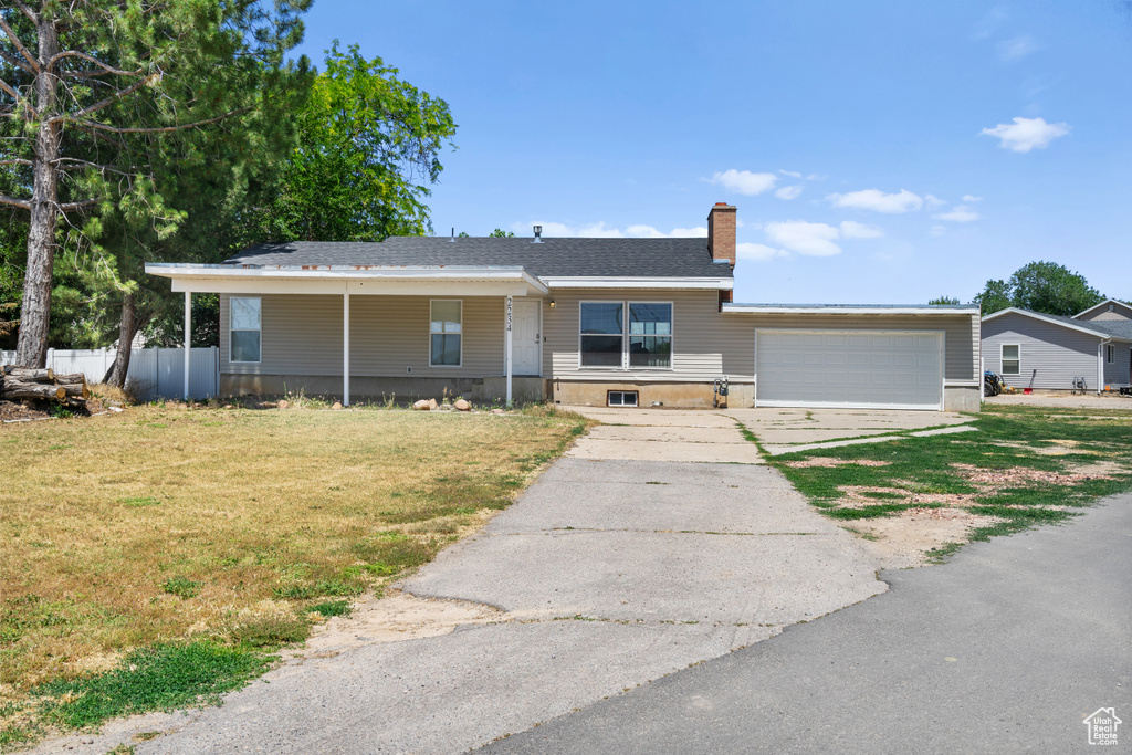 Ranch-style home featuring driveway, an attached garage, and a chimney