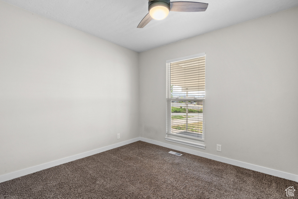 Unfurnished room with dark carpet and a ceiling fan