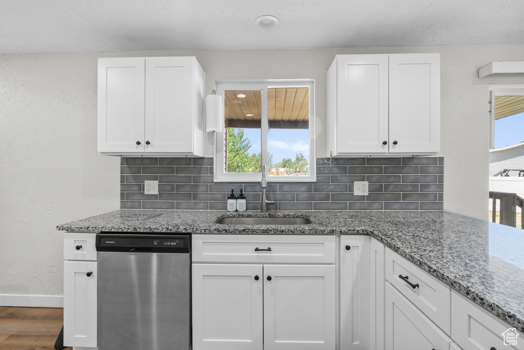 Kitchen featuring dishwasher, backsplash, white cabinetry, wood finished floors, and light stone countertops
