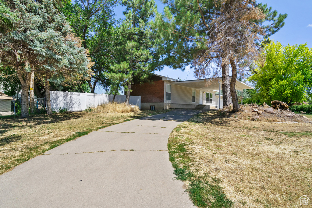 View of front of home with concrete driveway, a carport, and brick siding