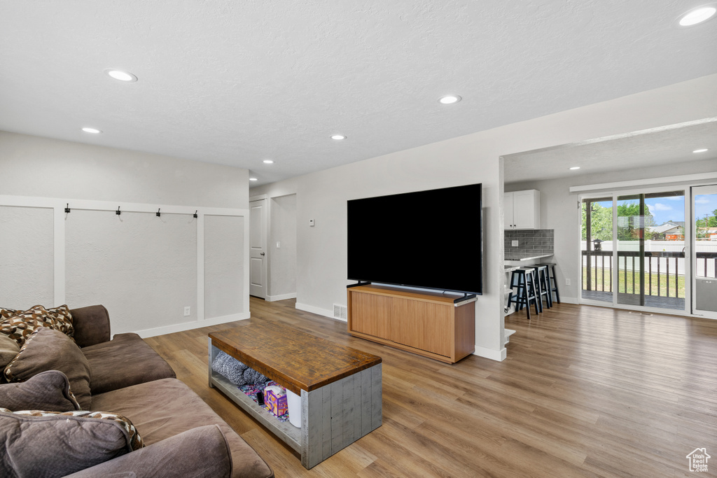Living room with light wood-style flooring and recessed lighting