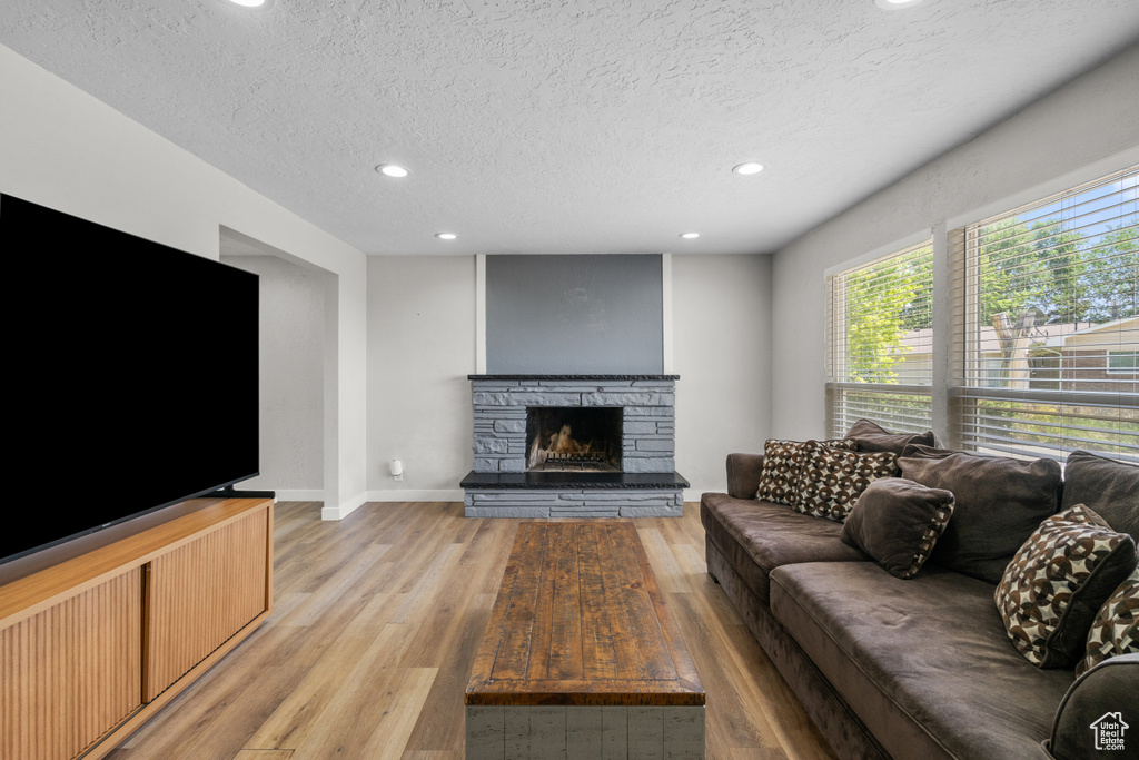 Living area with recessed lighting, light wood finished floors, a fireplace, and a textured ceiling