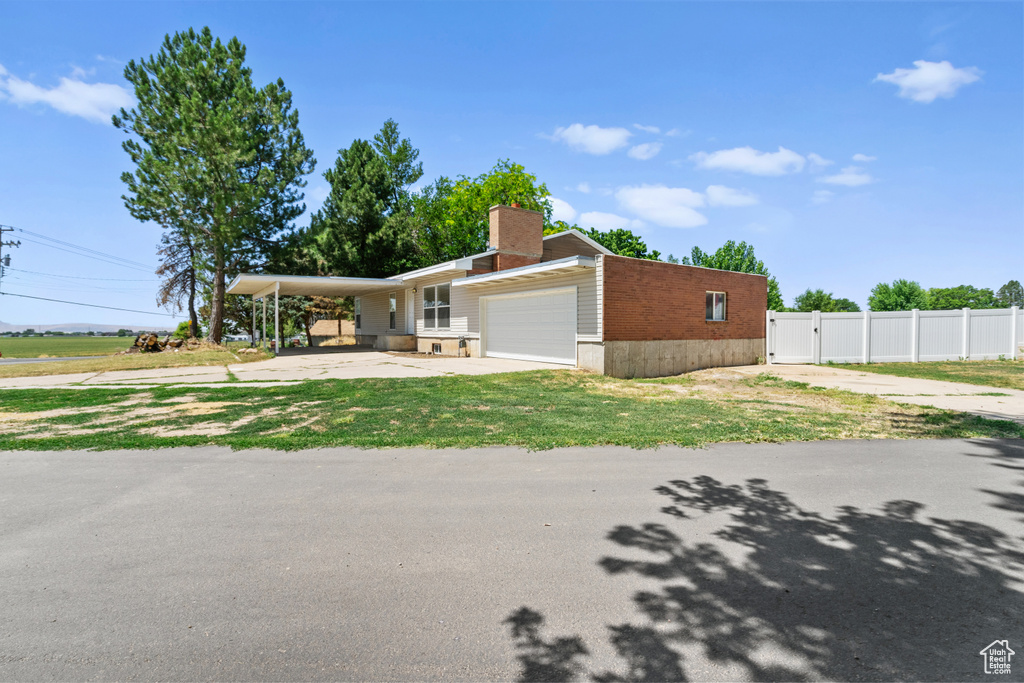 View of front of property with driveway, an attached garage, brick siding, and a carport