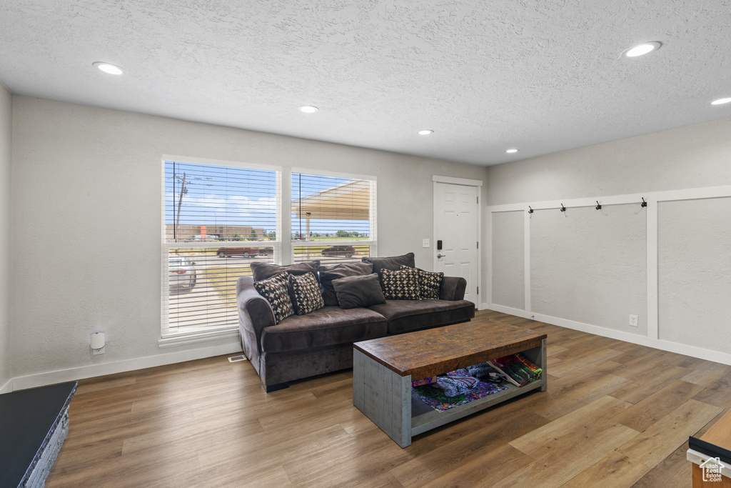 Living room with a textured ceiling, recessed lighting, and wood finished floors