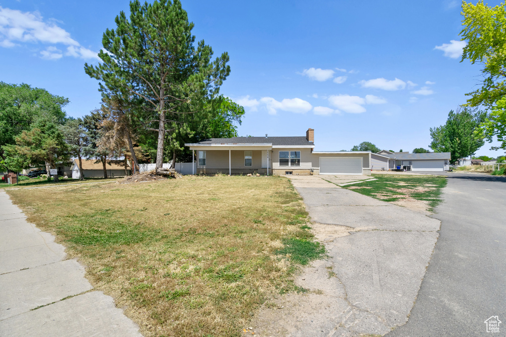 Single story home featuring a front yard, driveway, a chimney, and an attached garage