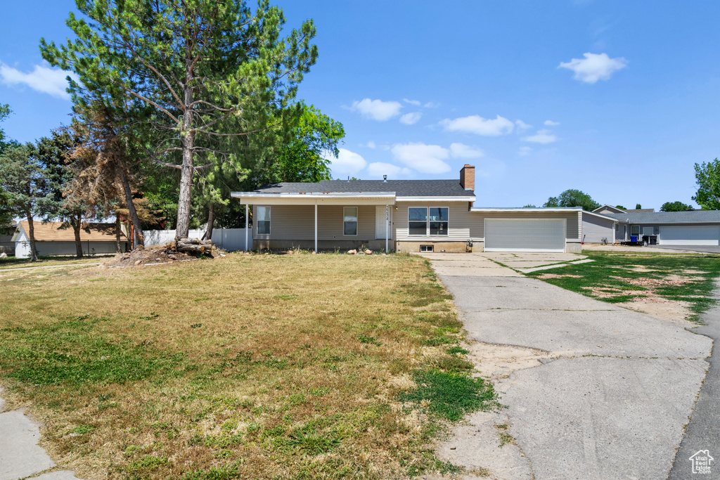 Single story home featuring an attached garage, a front lawn, and a chimney