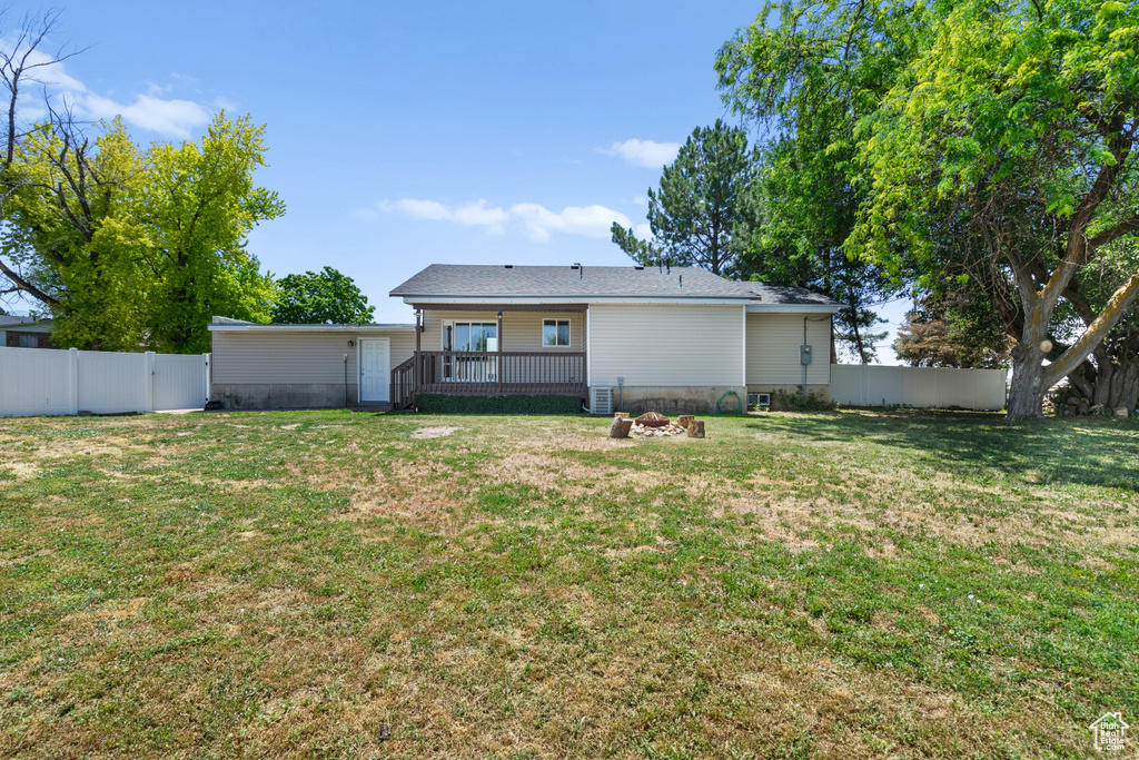 Rear view of property featuring a deck, a fire pit, and a fenced backyard