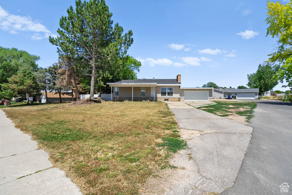 Single story home featuring a front yard, driveway, a chimney, and a garage