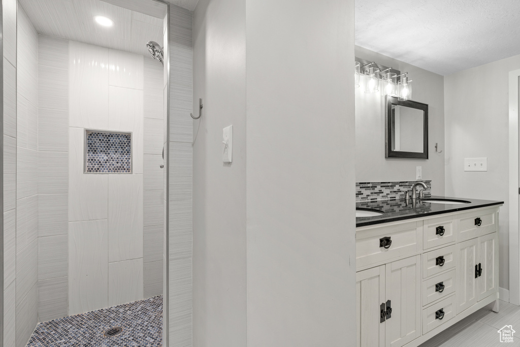 Bathroom featuring double vanity, a tile shower, decorative backsplash, and recessed lighting