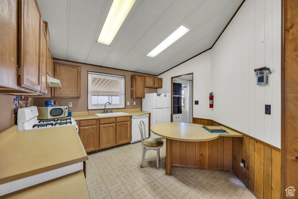 Kitchen with dishwasher, vaulted ceiling, light countertops, brown cabinetry, and under cabinet range hood