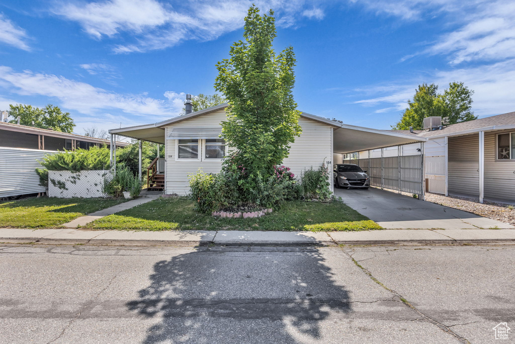View of front of home with asphalt driveway, an attached carport, and a front yard