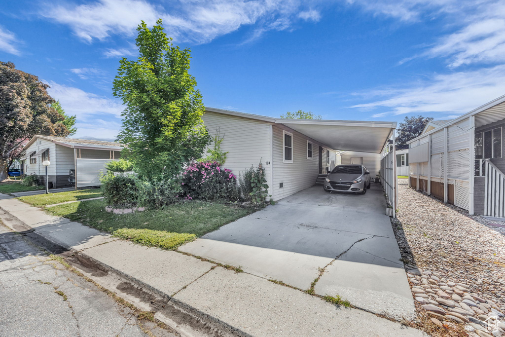View of front facade with driveway, an attached carport, and a front yard