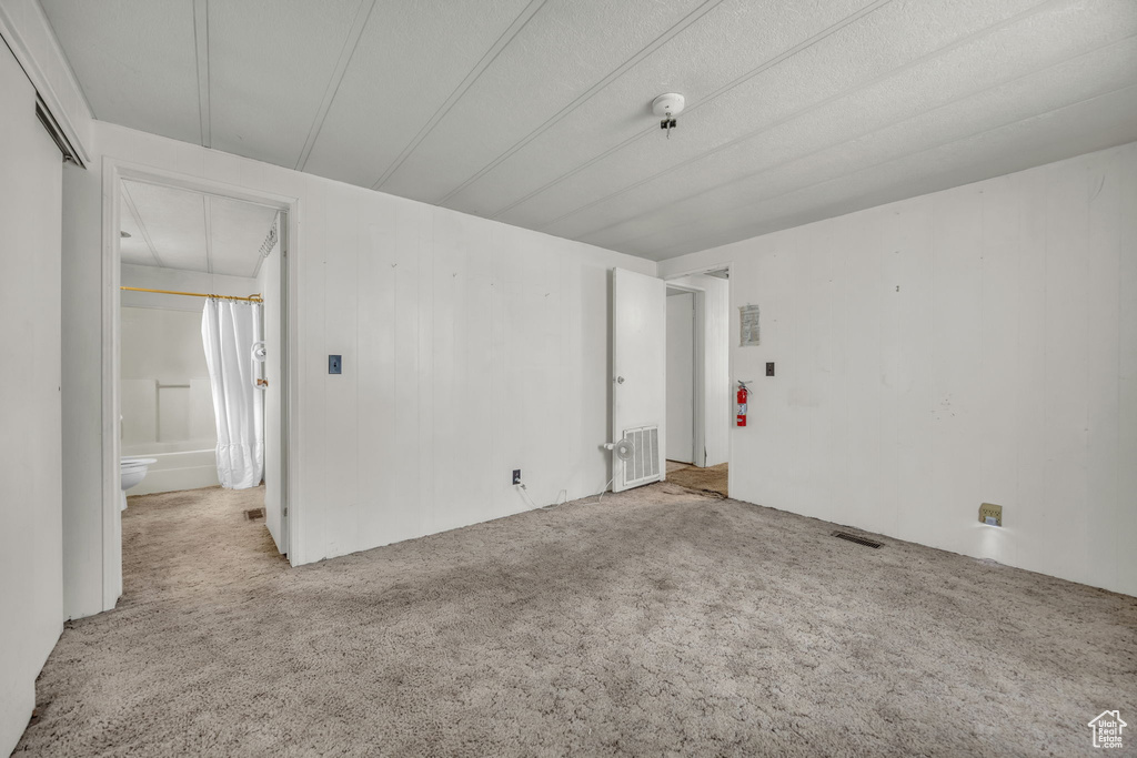 Empty room featuring carpet floors, a smoke detector, and attic access