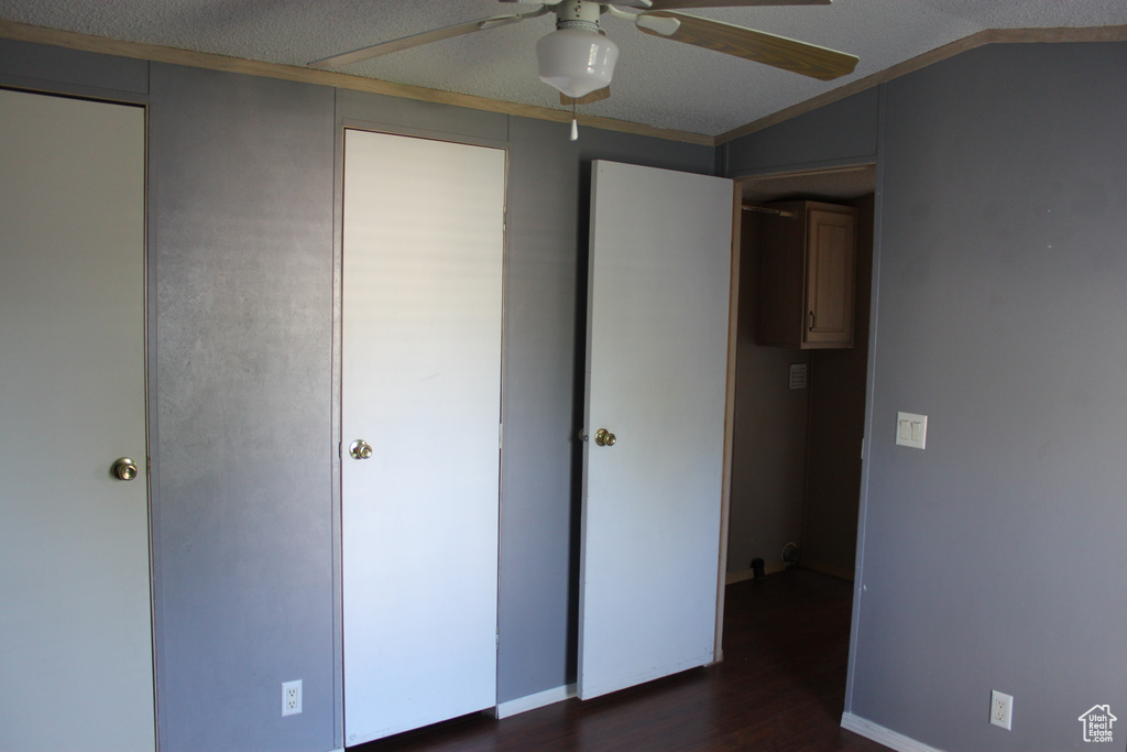 Unfurnished bedroom with dark wood-style floors, crown molding, and a ceiling fan