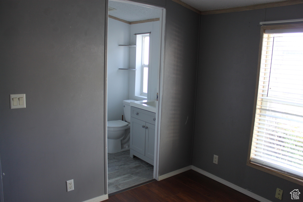 Unfurnished bedroom featuring dark wood-style floors, multiple windows, and ornamental molding