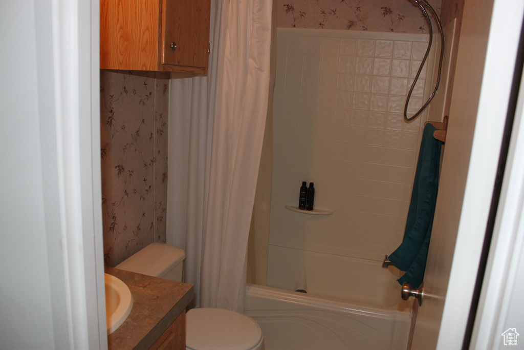 Full bath with vanity, shower / bath combo with shower curtain, and wallpapered walls