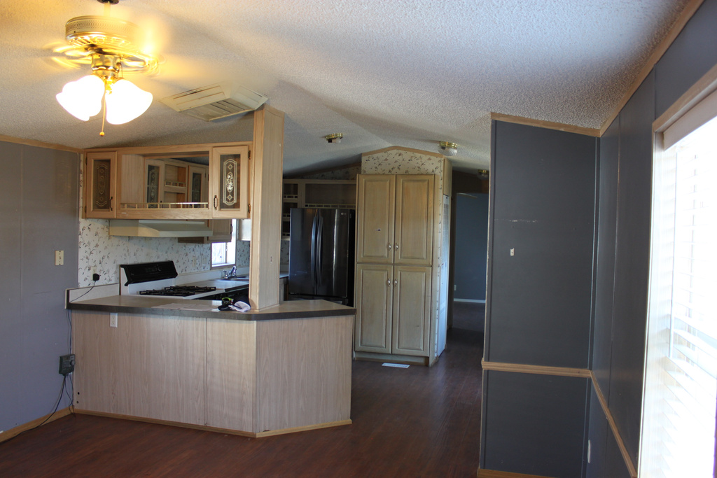Kitchen featuring freestanding refrigerator, range with gas stovetop, a peninsula, dark wood-style floors, and vaulted ceiling