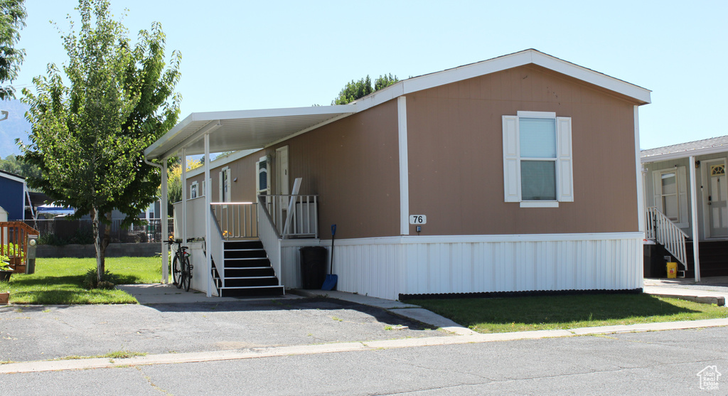 Manufactured / mobile home featuring an attached carport and a front yard