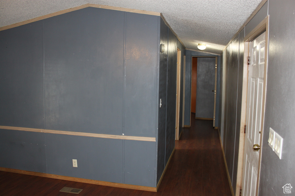Hall featuring wood finished floors, a textured ceiling, and lofted ceiling