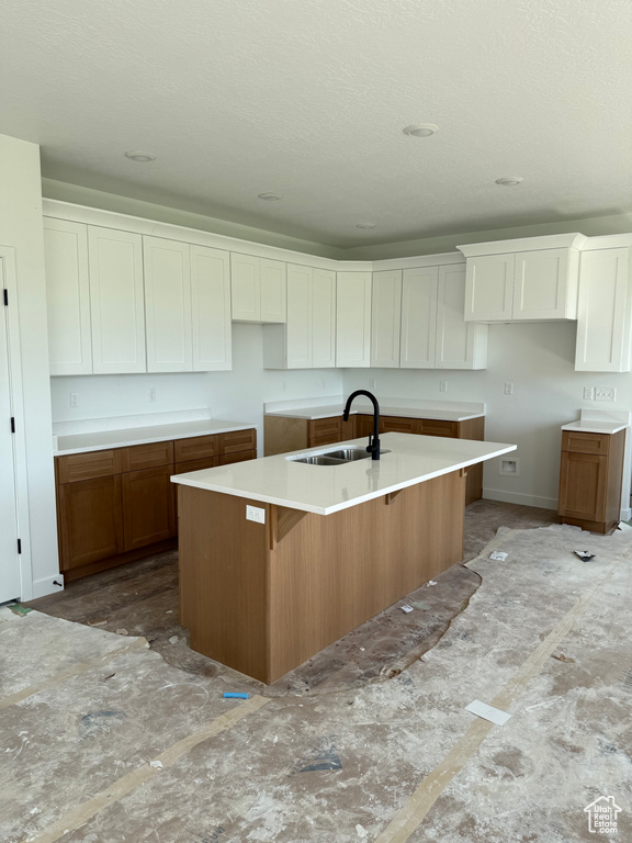 Kitchen featuring a kitchen island with sink, white cabinets, brown cabinets, and a kitchen bar