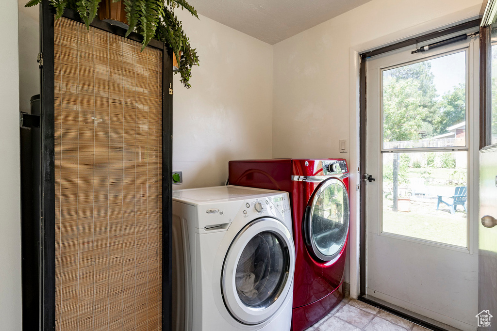 Laundry area featuring washer and clothes dryer, plenty of natural light, and light tile patterned floors