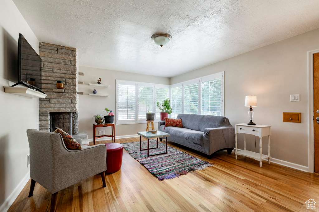 Living area featuring wood finished floors, a fireplace, and a textured ceiling