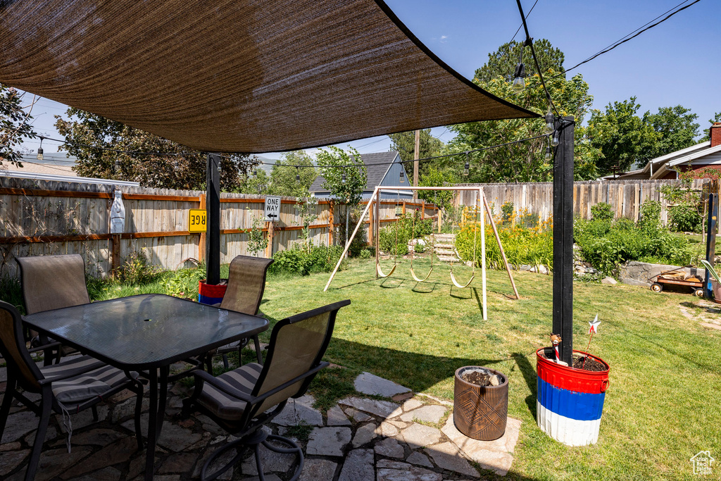 Fenced backyard featuring outdoor dining space, a playground, and a patio area