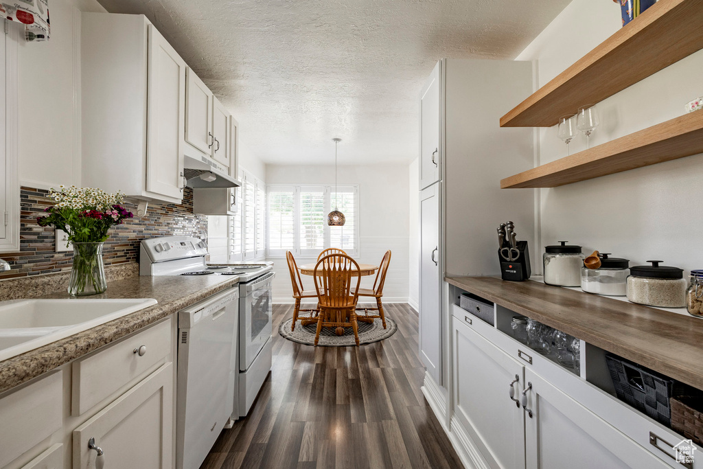 Kitchen with white appliances, under cabinet range hood, dark wood-type flooring, a textured ceiling, and wood counters