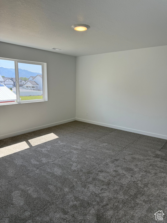 Empty room featuring dark carpet and baseboards