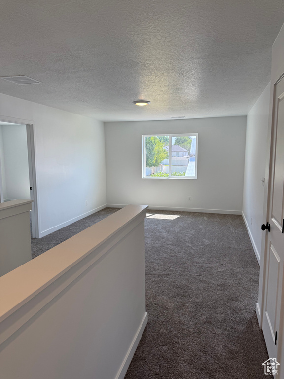 Carpeted empty room with a textured ceiling