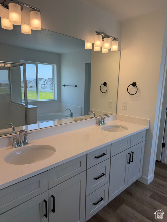 Full bath with double vanity, wood finished floors, a garden tub, and a shower stall